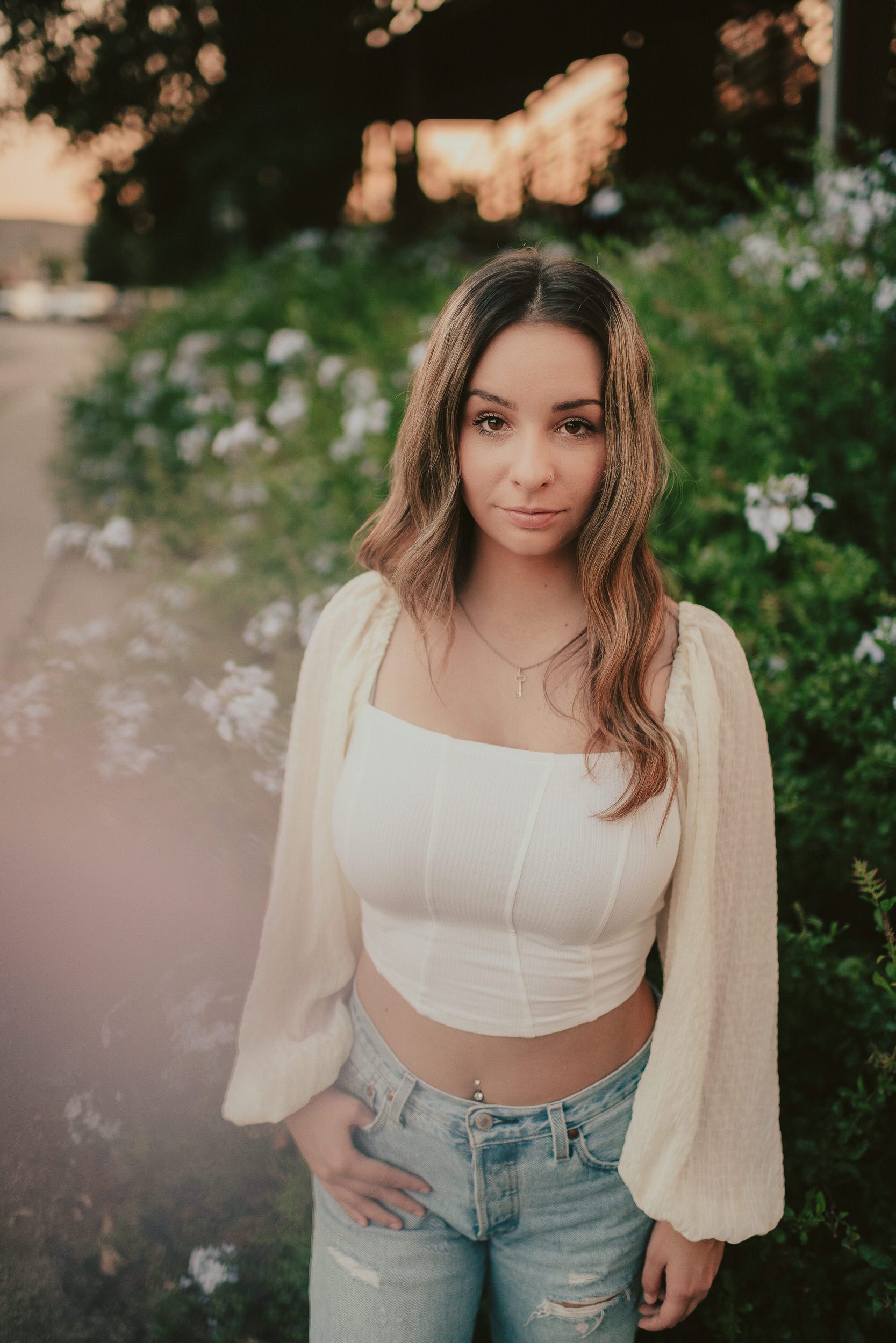 Soft senior portrait framed by greenery and foreground haze