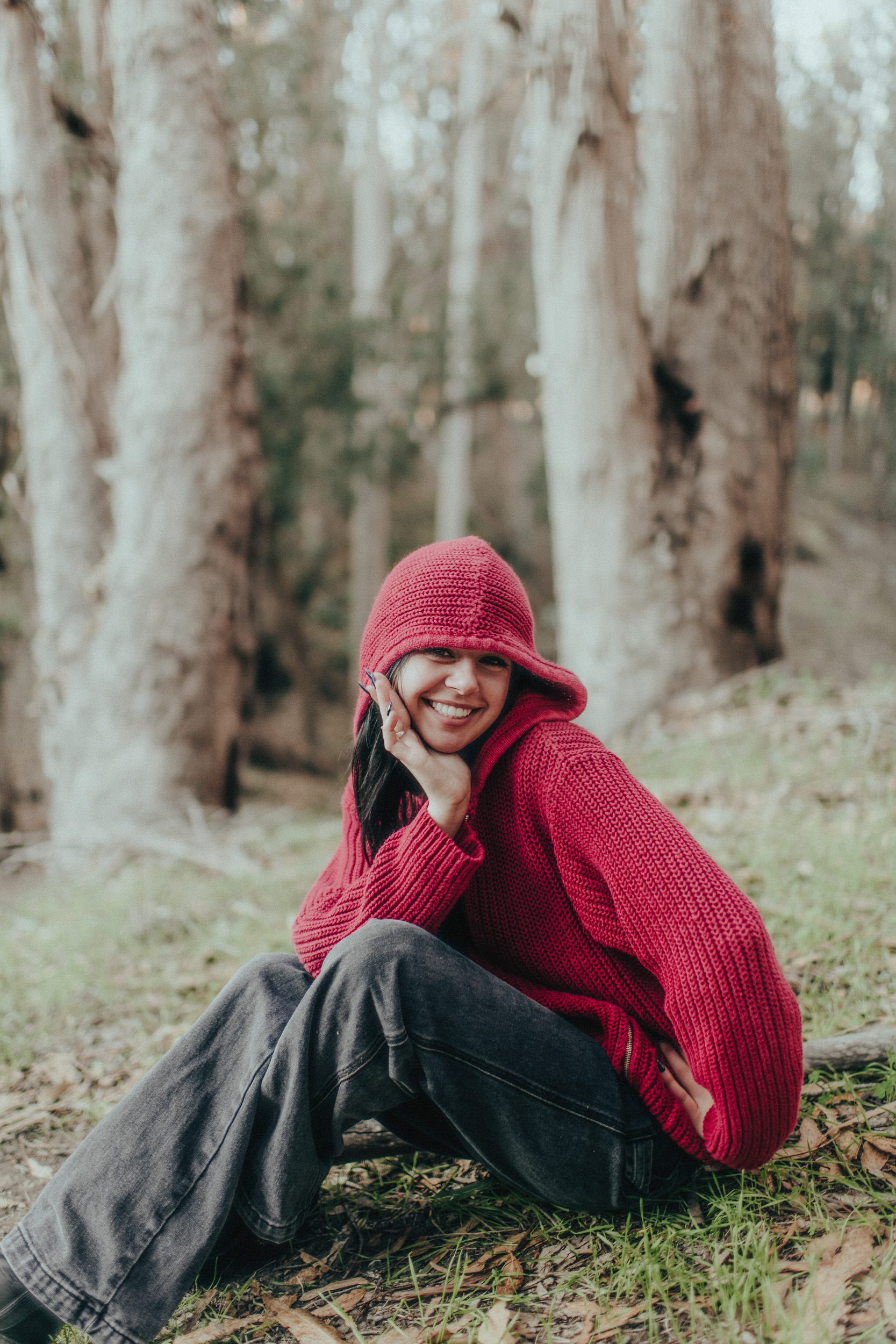 Playful seated senior portrait in a forest setting