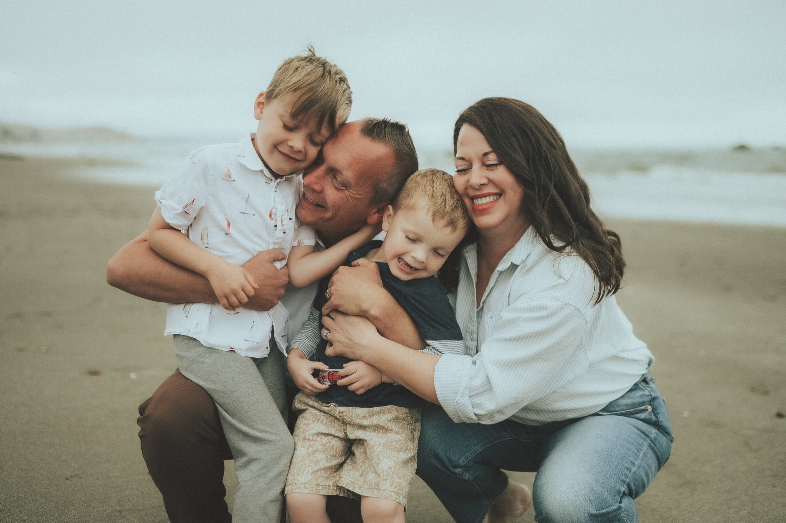 The Schulte family cuddling and laughing together on the beach