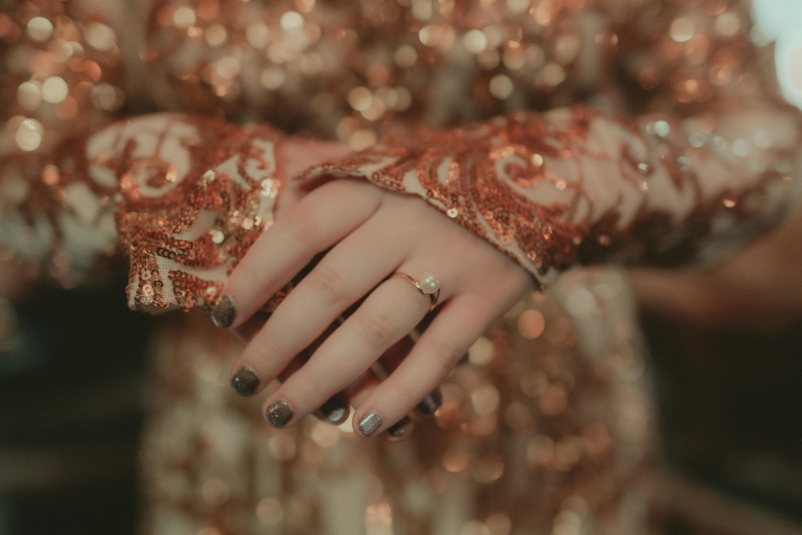 A pearl ring and glittering wedding attire photographed in close detail
