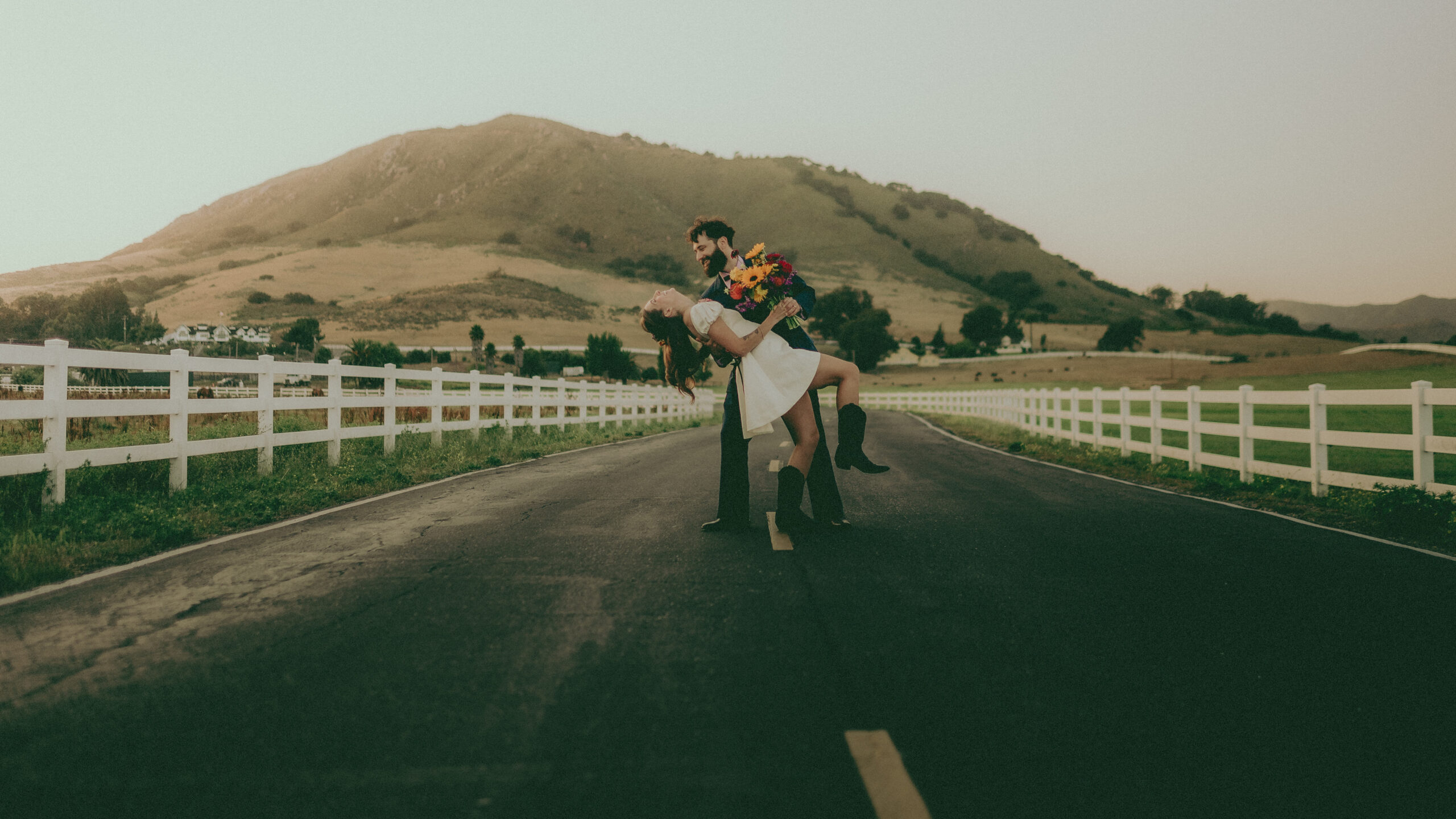 Emma and Jesse pose on a quiet road with rolling hills behind them