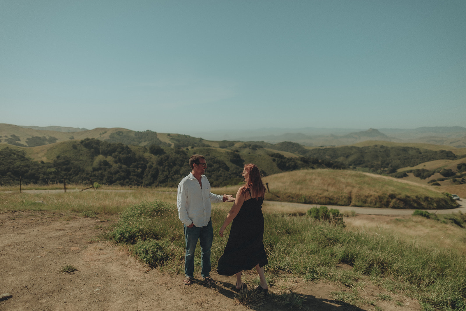 Engaged couple in a wide portrait among rolling coastal hills