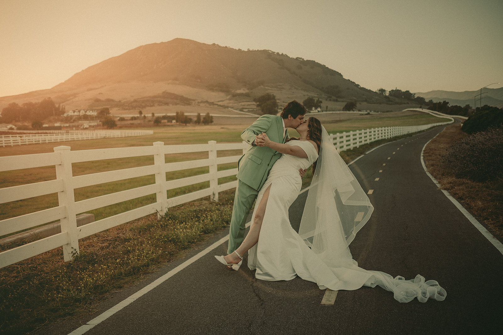 Newlyweds standing on a country road at sunset near the Madonna Inn