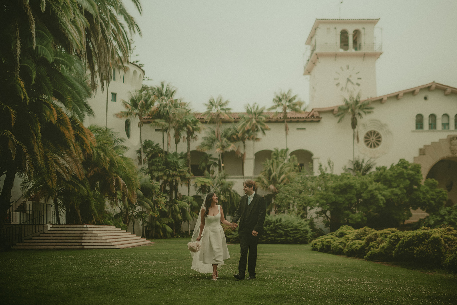 Alexandria and Jason holding hands on the Santa Barbara Courthouse lawn.