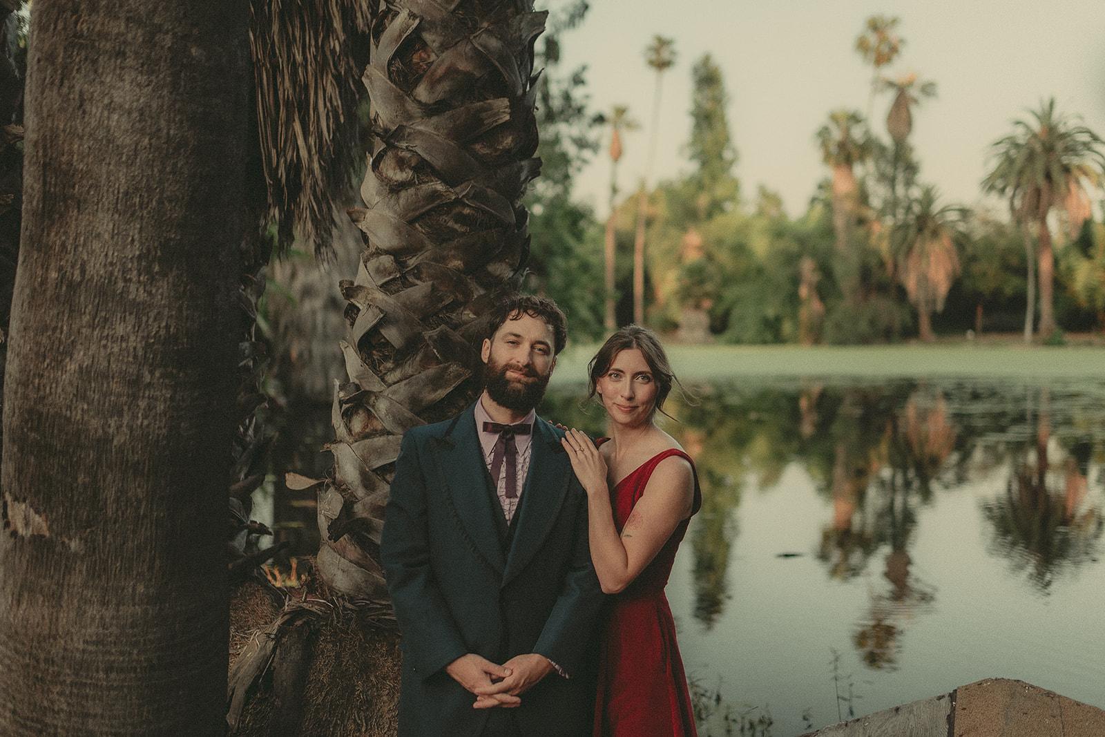 Couple framed by a tree beside a garden pond and architecture