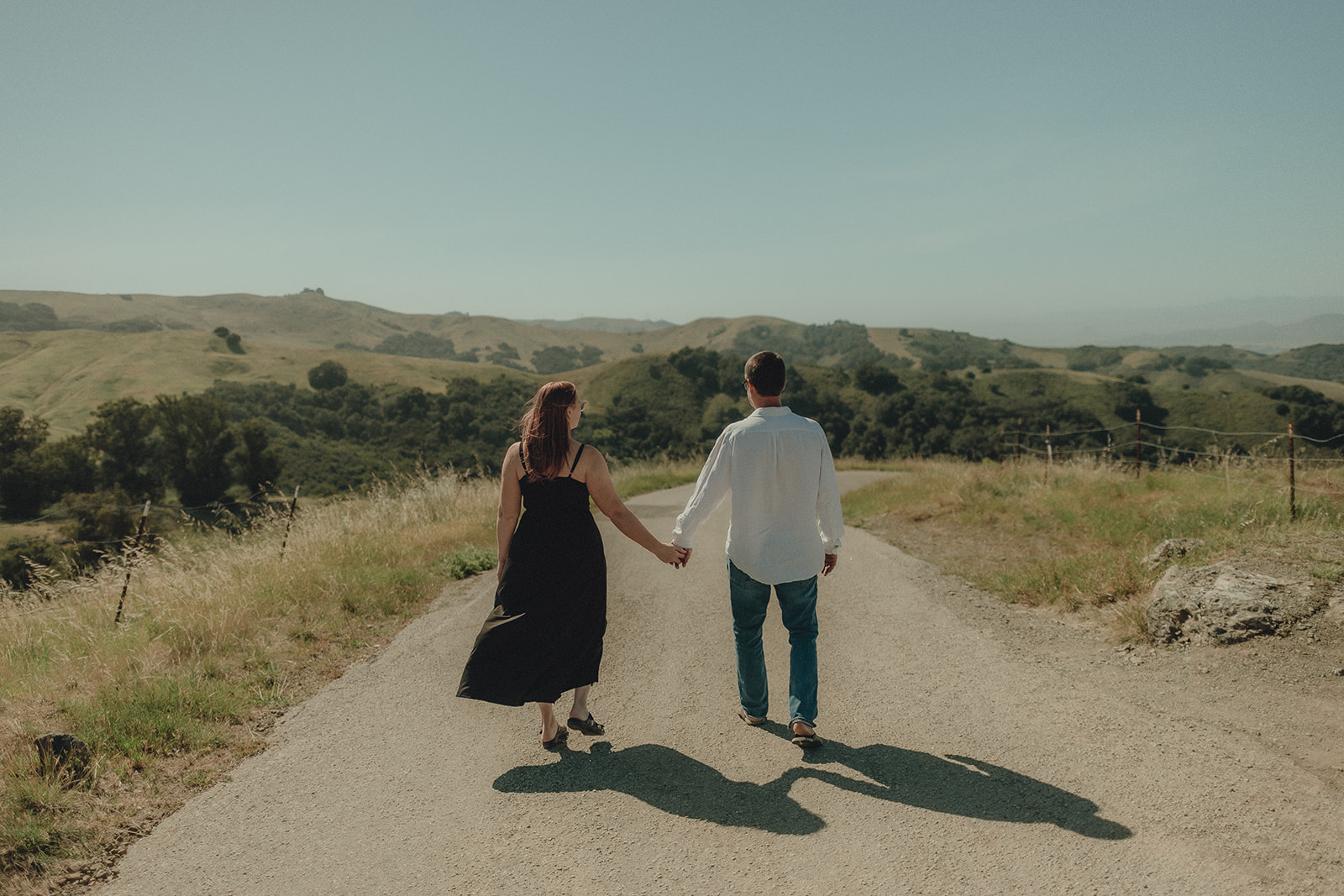 Couple walking hand in hand down an open country road