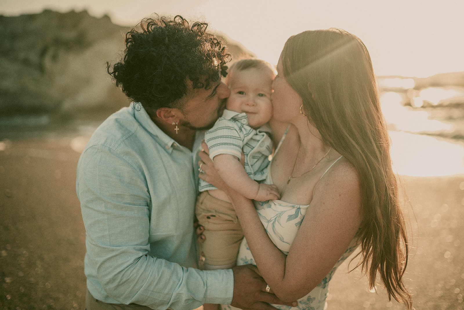 Parents holding their baby in warm sun-flared light