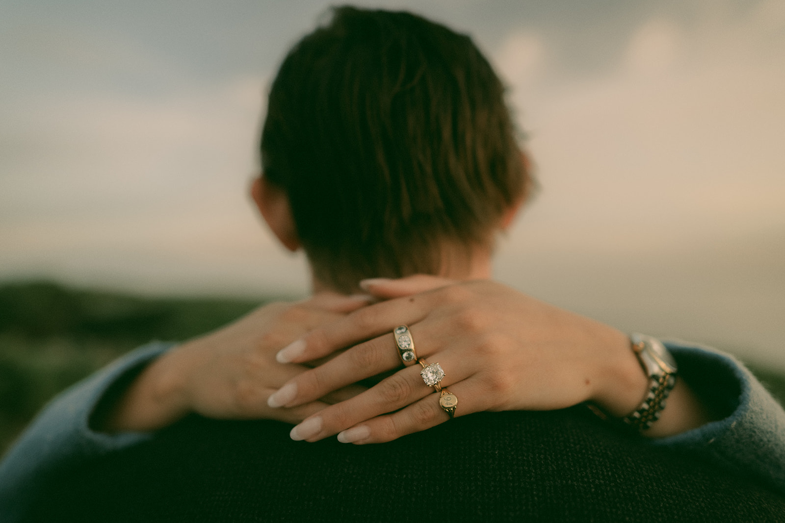 Engagement ring visible over a partner's shoulder during an embrace