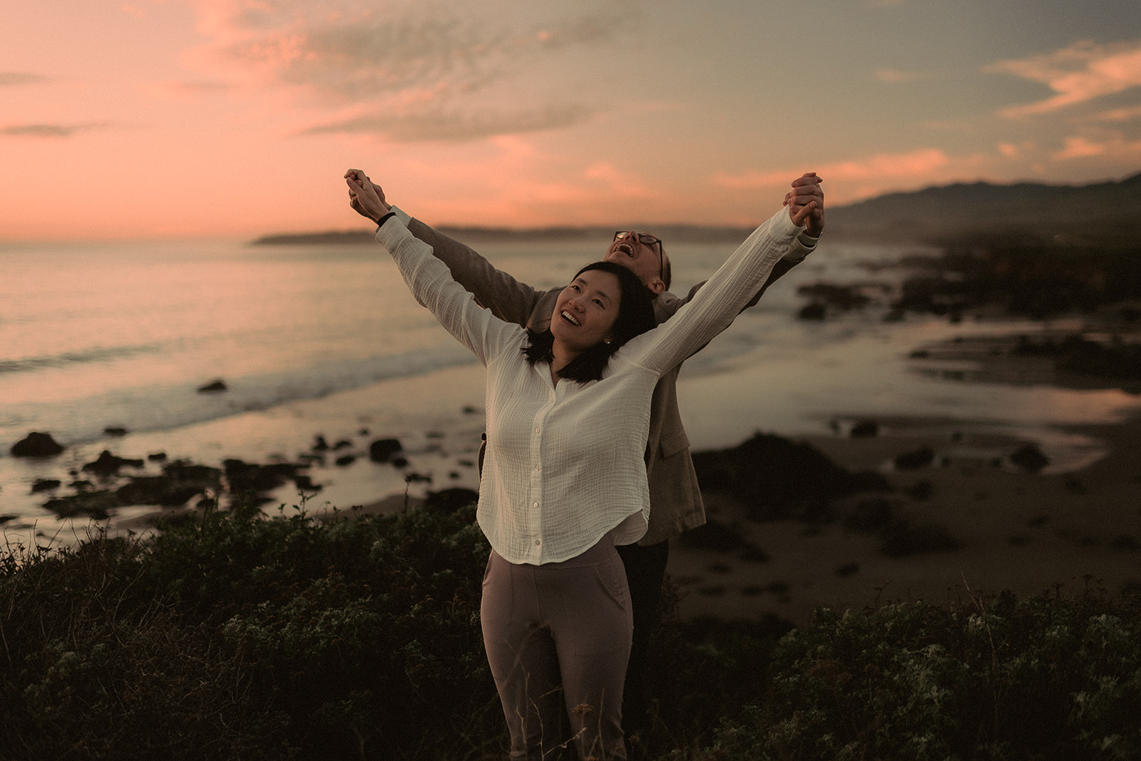 Celebratory reaction with arms open beside the coast