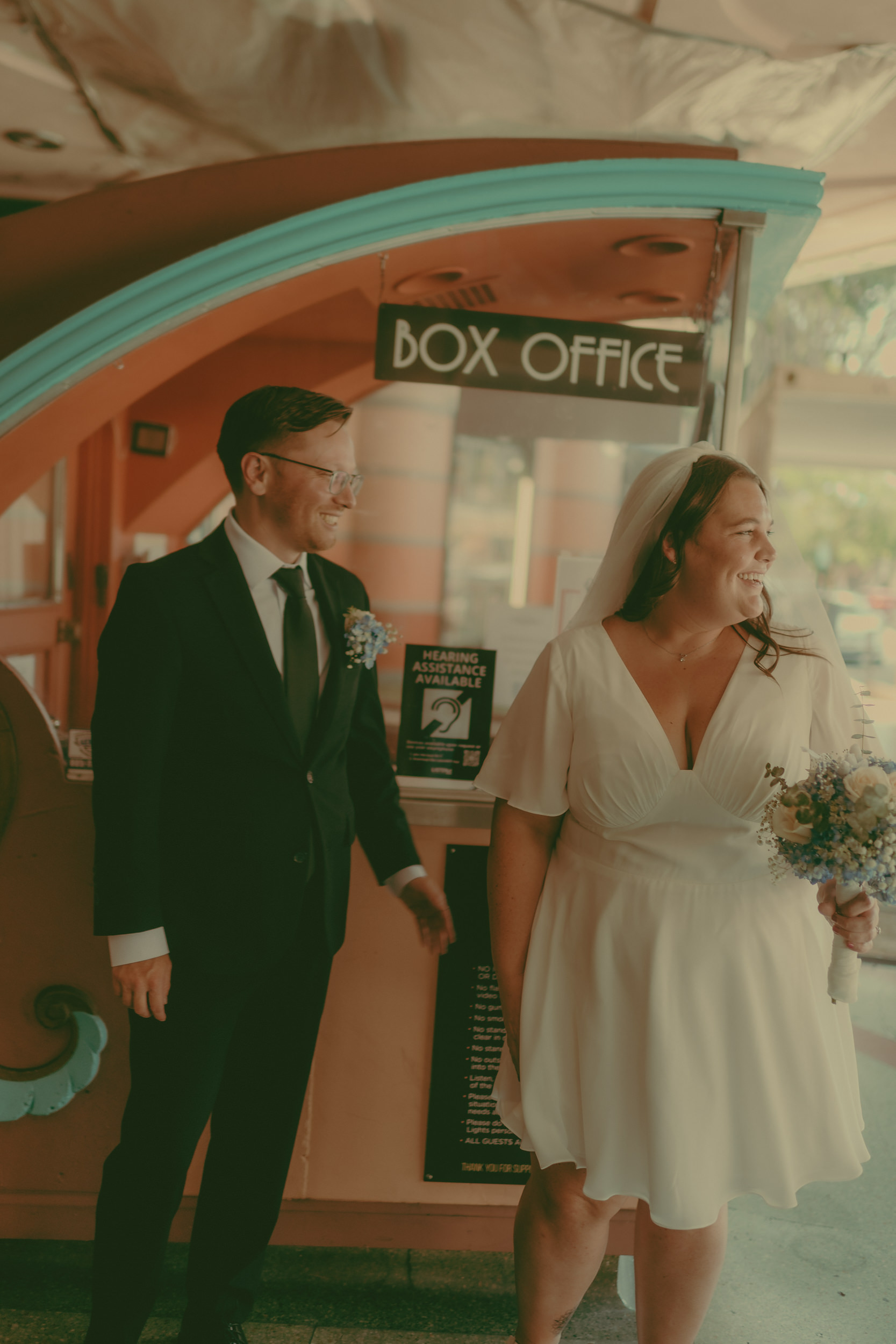 Tiffani and Braden laugh beside the small downtown Box Office booth.