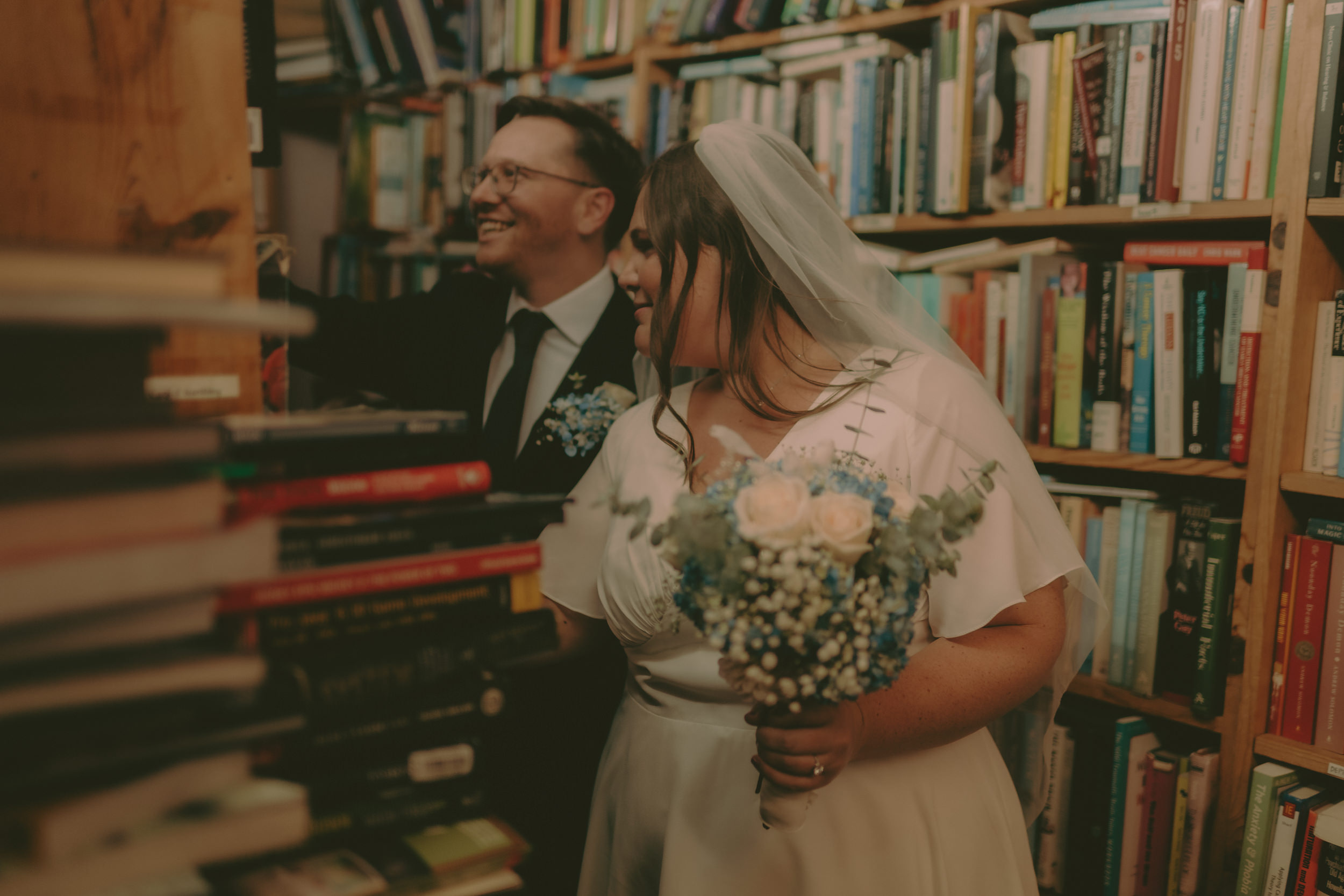 Tiffani and Braden laugh together between bookstore shelves.