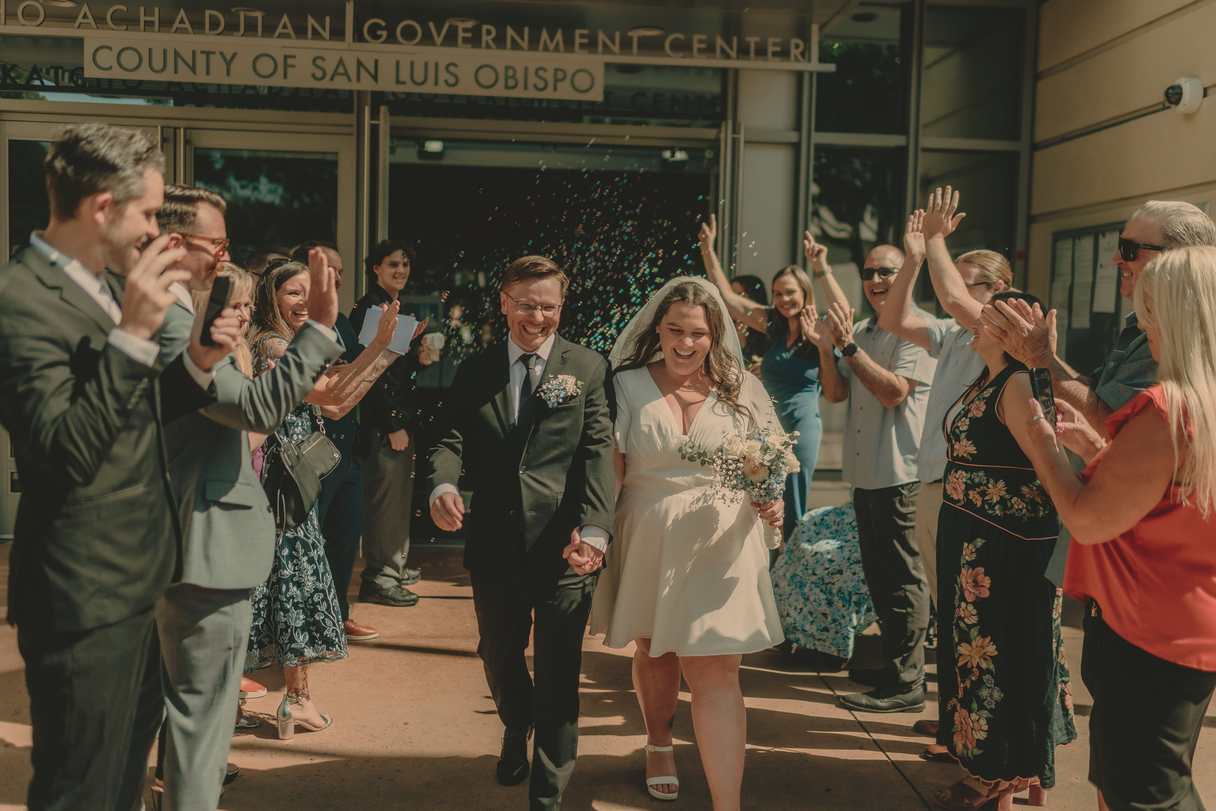 Tiffani and Braden leave the courthouse through a tunnel of bubbles and cheering guests.