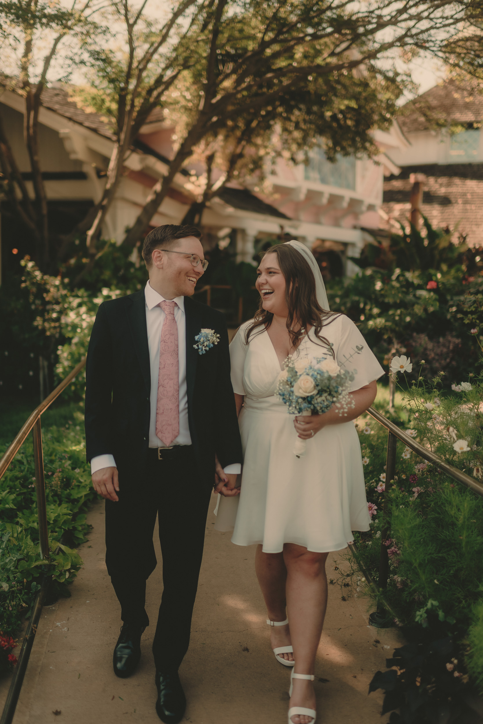 Tiffani and Braden laugh together on a flower-lined garden path.