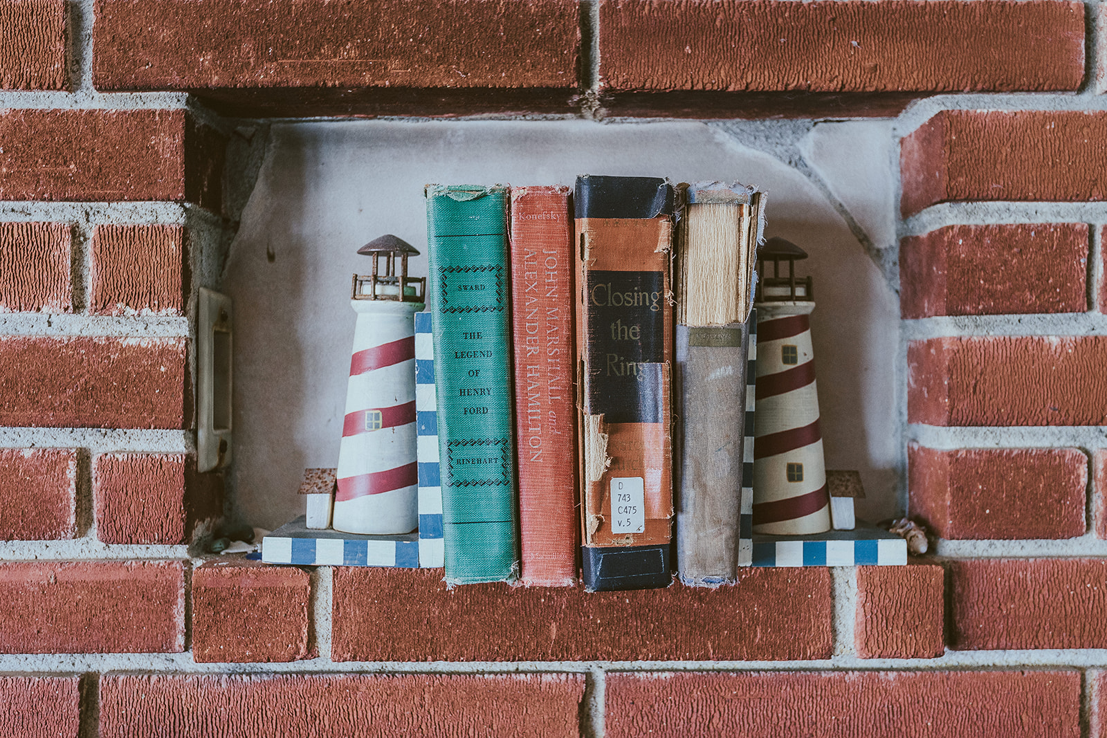 Brick architectural niche with books and lighthouse decor in a coastal rental