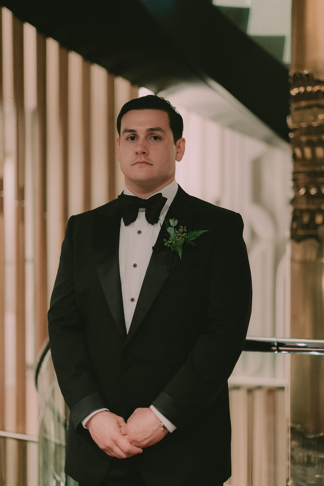 Charles stands in a black tuxedo beside the curved staircase at The Jay Hotel.