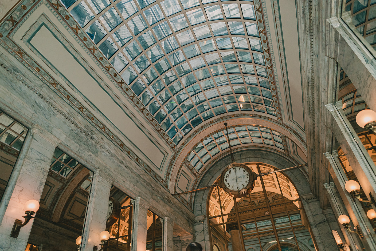 Wide architectural view of the Julia Morgan Ballroom clock beneath a glass and marble ceiling.