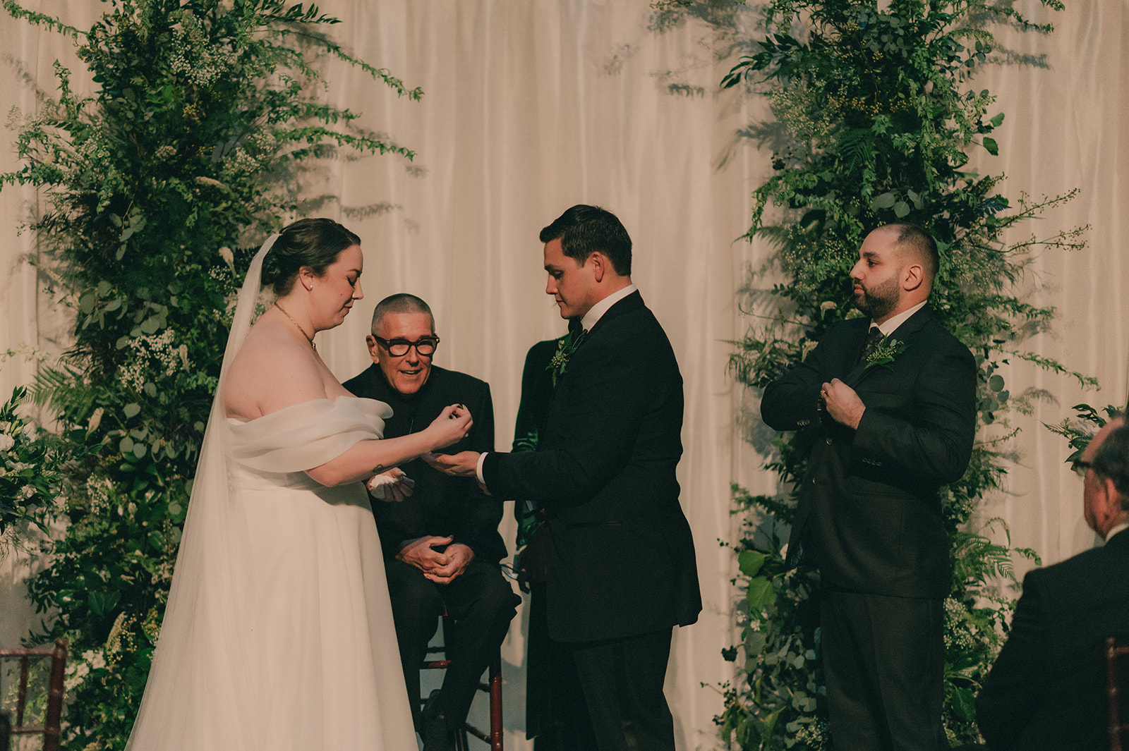 Anne places a ring on Charles's hand during their green-and-white ceremony.