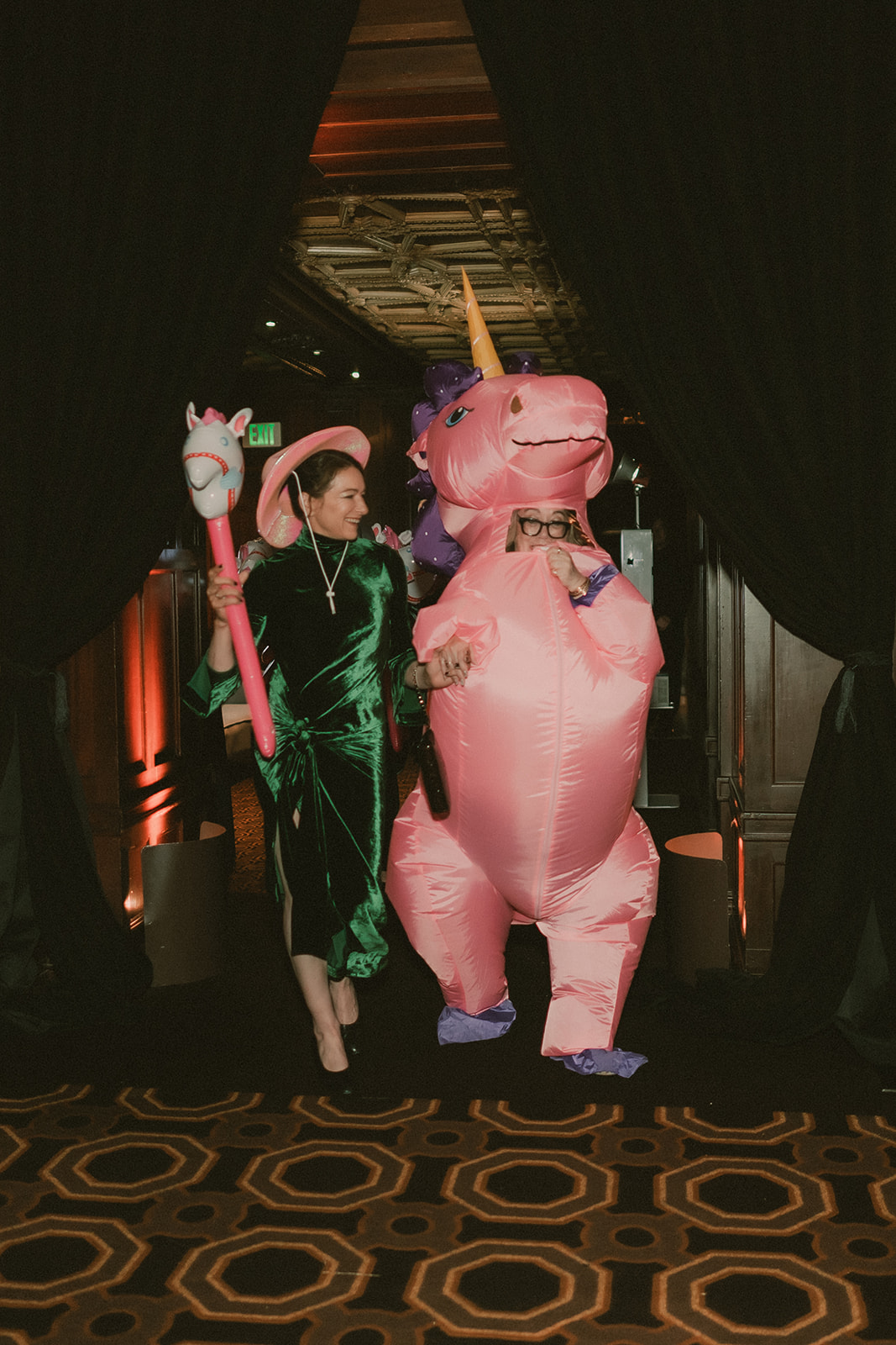 Two wedding guests make a playful entrance with a pink inflatable pony costume and hobby horse.