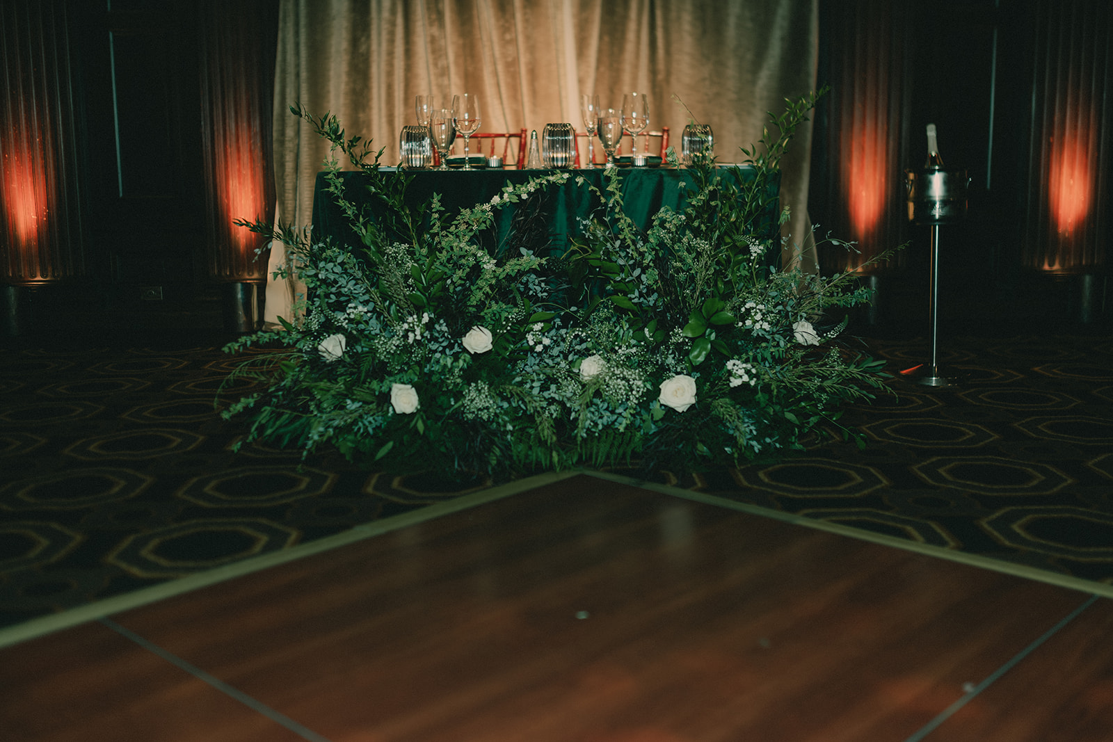 White roses and greenery around a candlelit wedding table