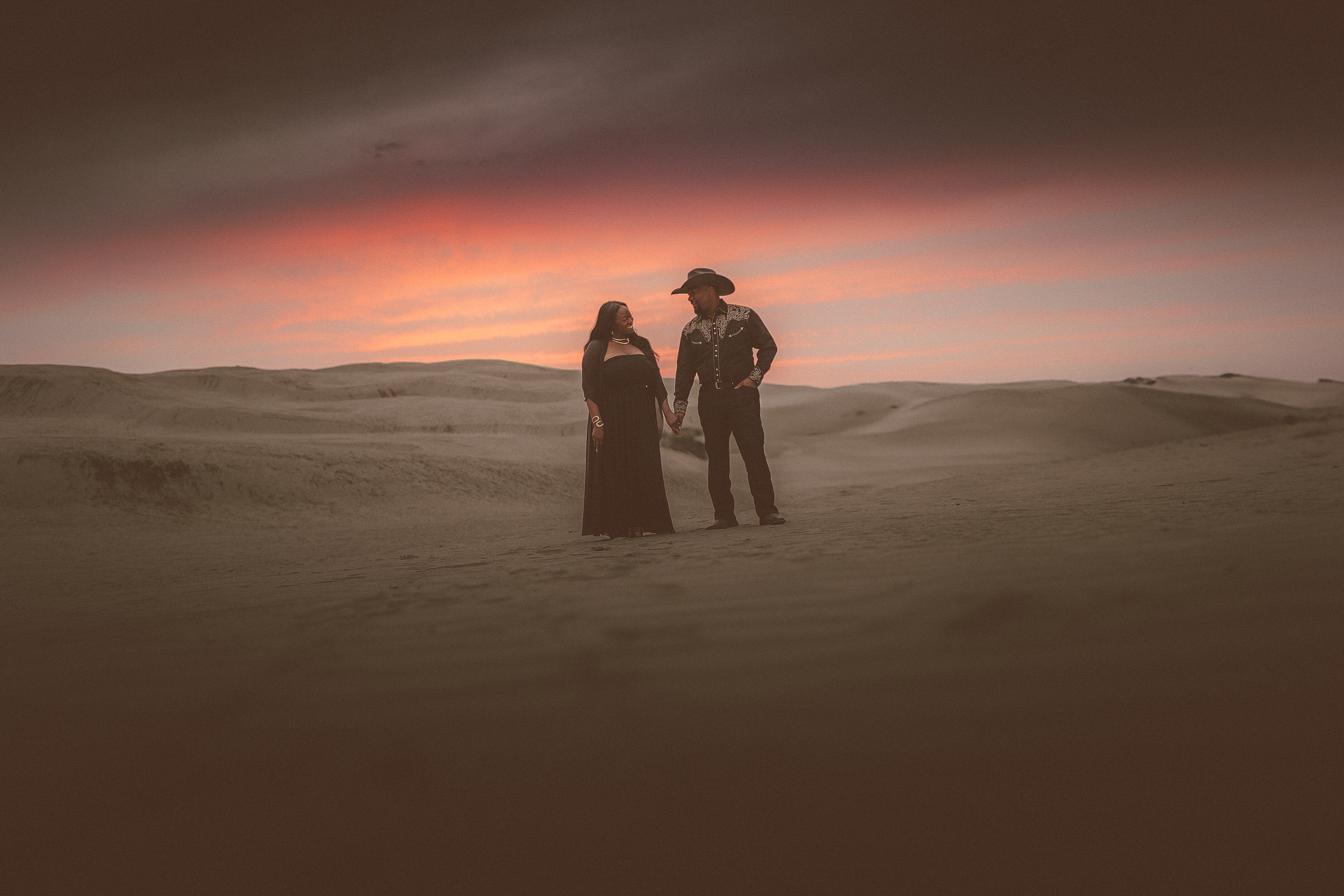 Shanaya and Joshua together among rolling Oceano sand dunes at sunset