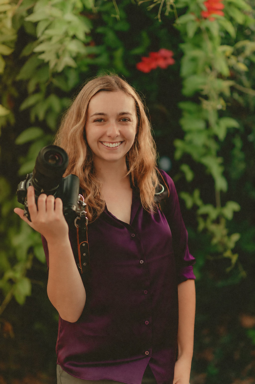 Makayla Grogan smiling with her camera outdoors.